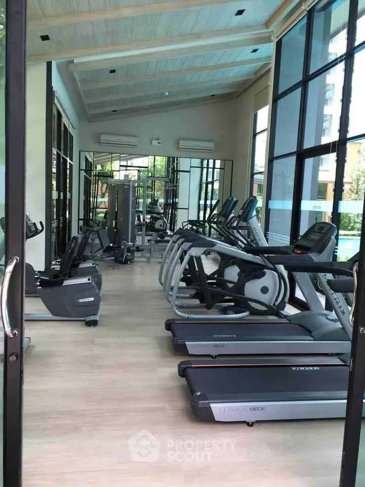 Modern gym with state-of-the-art equipment and large windows in a luxury building.