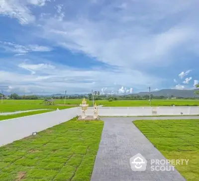 Expansive green garden with scenic mountain views and clear blue sky