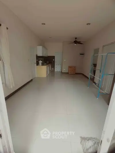 Spacious open-plan living area with modern kitchen and ceiling fan, perfect for comfortable living.