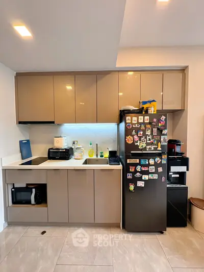 Modern kitchen with sleek cabinets and fridge adorned with magnets.