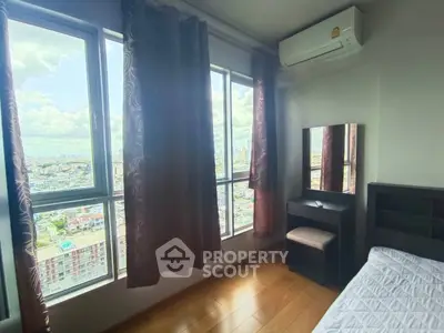 Bright bedroom with large windows offering stunning city views, featuring air conditioning and modern furnishings.