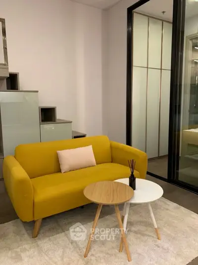 Modern living room with yellow sofa and stylish coffee tables in cozy apartment.
