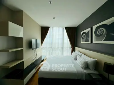 Modern bedroom with stylish decor and large window offering natural light.