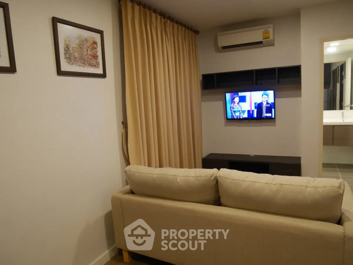 Cozy living room with beige sofa and wall-mounted TV, perfect for relaxation.