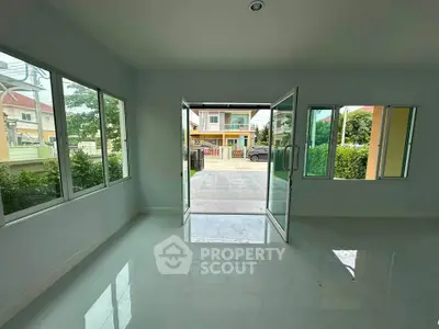 Spacious living room with large windows and open doors leading to a bright outdoor area.