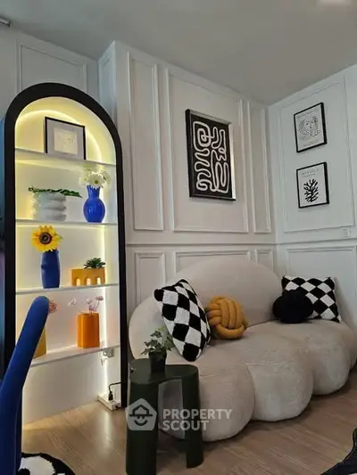 Chic living room with modern decor, featuring a cozy sofa, stylish shelving, and contemporary wall art.