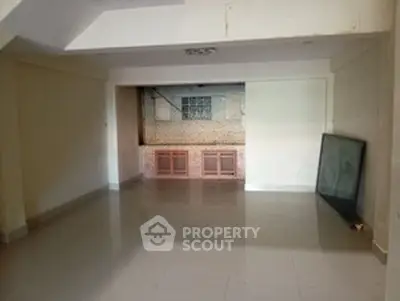 Spacious empty room with tiled flooring and a large window, ideal for customization.