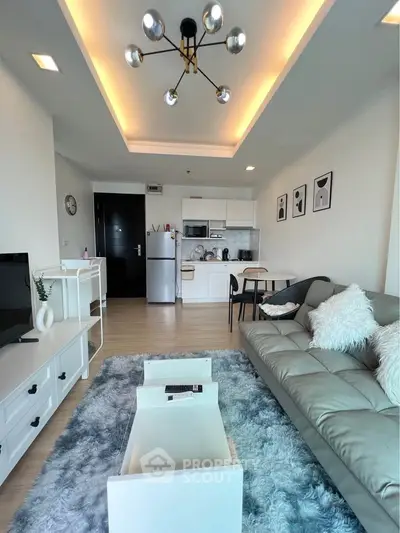 Modern living room with open kitchen, stylish decor, and cozy ambiance.