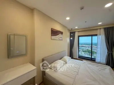Modern bedroom with large window offering stunning city view, featuring elegant decor and cozy ambiance.