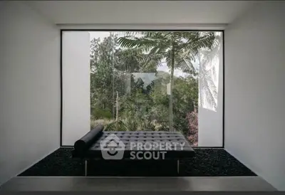 Modern minimalist interior with large window showcasing lush greenery view.