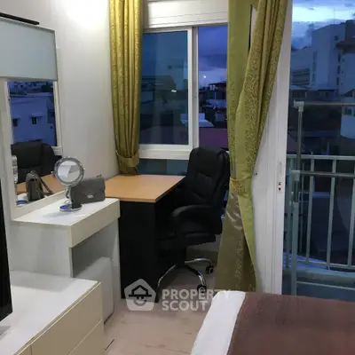 Cozy bedroom with desk and balcony view, perfect for work and relaxation.