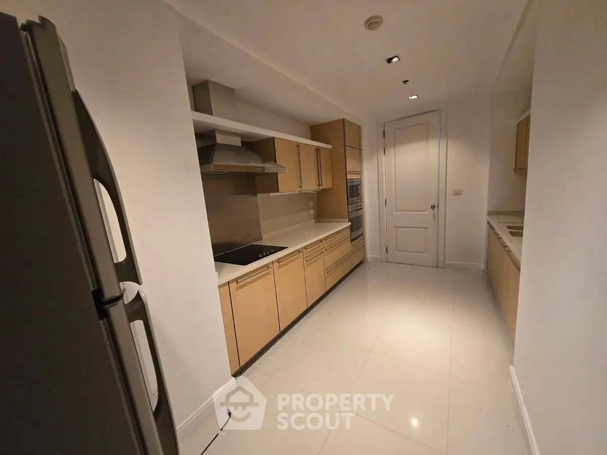Spacious modern kitchen with sleek cabinetry and built-in appliances in a luxury apartment.