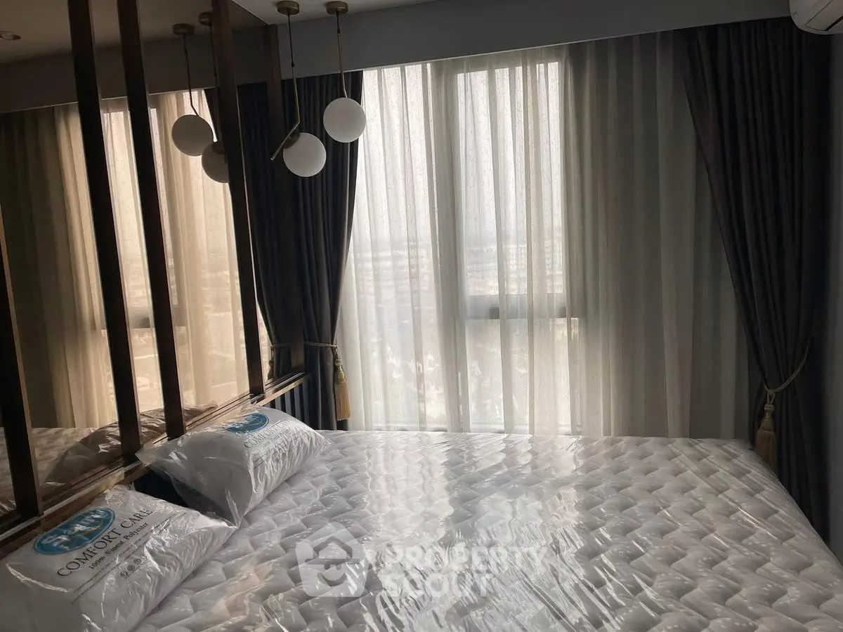 Modern bedroom with large window and elegant curtains, featuring a comfortable bed and stylish lighting.