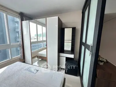 Modern bedroom with large windows and sleek furniture in a high-rise apartment.
