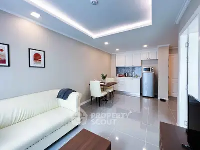 Modern open-layout living room with sleek kitchen and dining area, featuring elegant furniture and contemporary design.