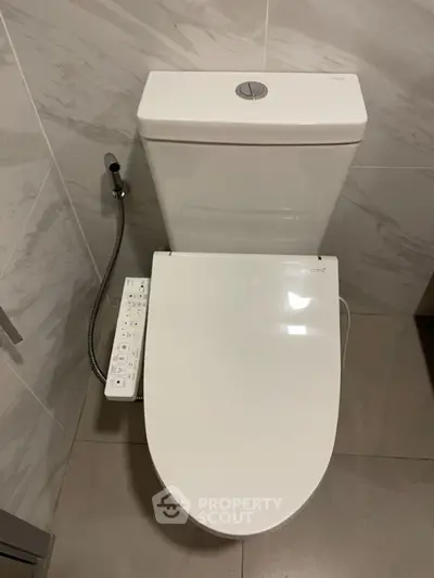 Modern bathroom with sleek toilet and bidet attachment in a contemporary setting.