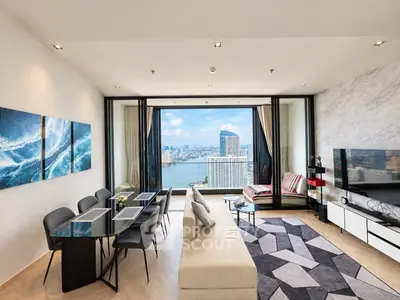 Luxurious living room with stunning city and river view, modern decor, and spacious seating area.