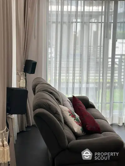 Elegant living room with plush sofa and sheer curtains, offering a cozy and inviting atmosphere.