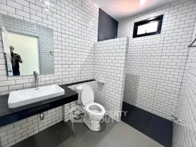 Modern bathroom with sleek white subway tiles and open shower design.