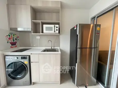 Modern kitchen with sleek appliances including fridge, washing machine, and microwave in compact layout.