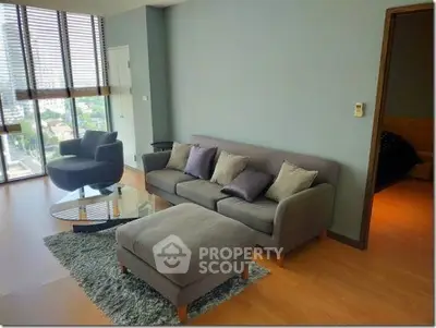 Modern living room with stylish furniture and large windows offering city views.