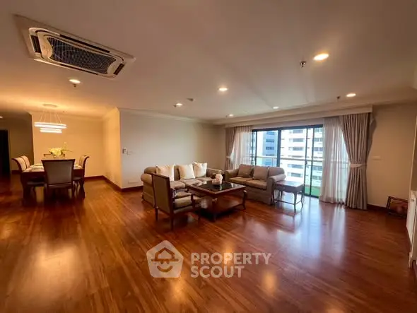 Spacious living room with elegant wooden flooring and large windows offering city views.