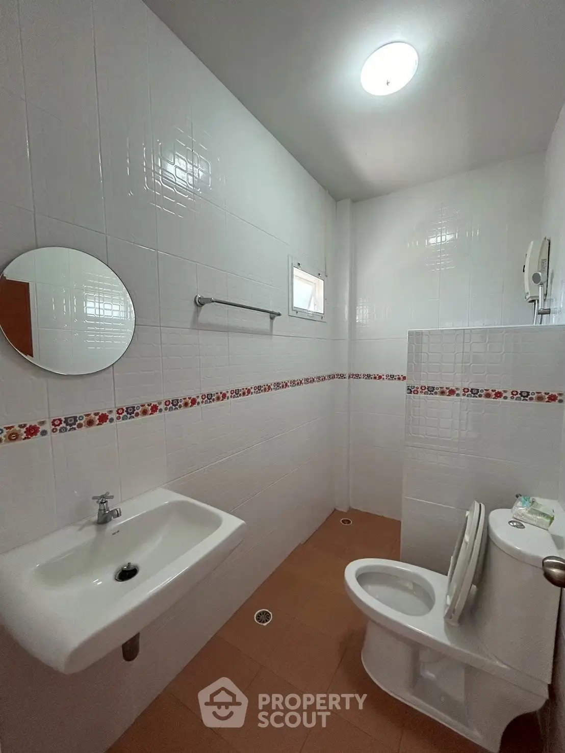 Compact bathroom with white tiles, round mirror, and modern fixtures in a cozy real estate property.