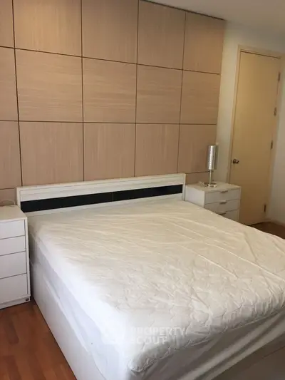 Spacious bedroom with modern design and wooden accents, featuring a comfortable bed and stylish nightstands.