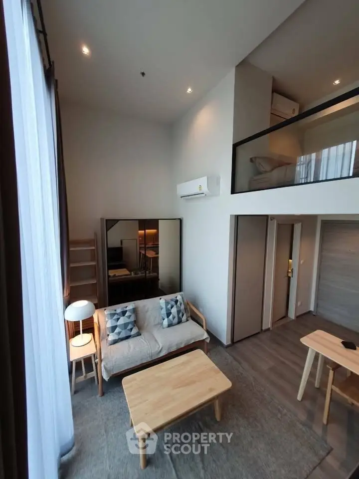 Modern loft apartment with high ceilings and mezzanine bedroom, featuring stylish furniture and large windows.