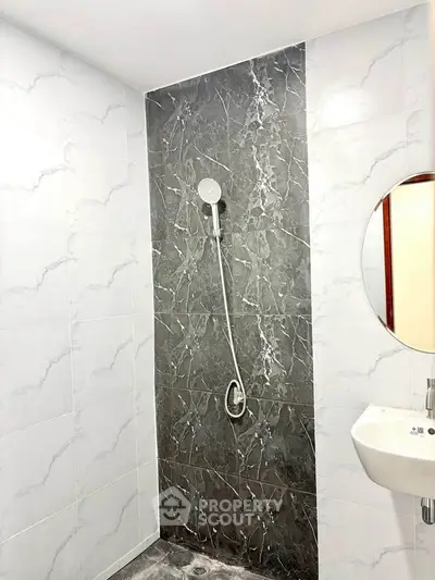Modern bathroom with elegant marble shower and sleek white sink.