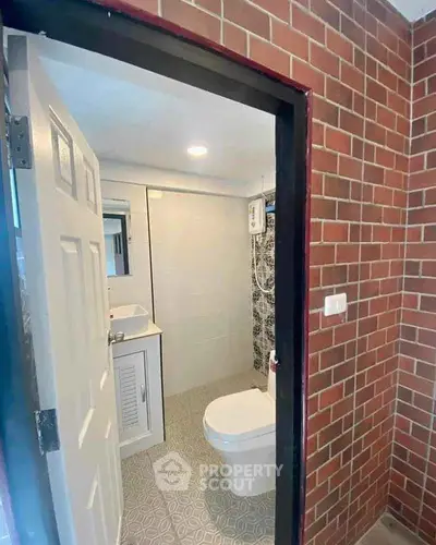 Modern bathroom with brick wall entrance and white fixtures