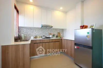 Modern kitchen with sleek cabinets and stainless steel fridge in a cozy apartment.