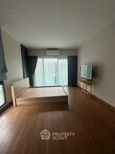 Spacious bedroom with large windows and wooden flooring in modern apartment