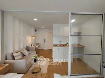 Modern open-plan living room with sleek kitchen and cozy seating area in a stylish apartment.