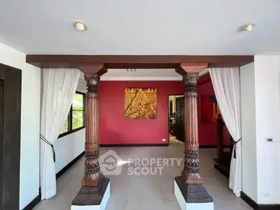 Elegant living room with ornate wooden columns and vibrant red accent wall