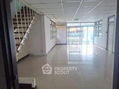 Spacious open-plan living area with staircase and large windows for natural light.