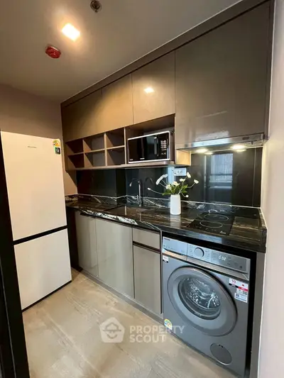 Modern kitchen with sleek cabinets, washing machine, and built-in appliances.