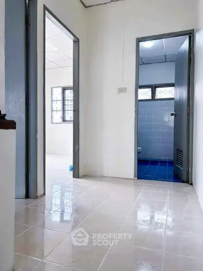 Bright hallway leading to rooms with tiled floors and natural light.