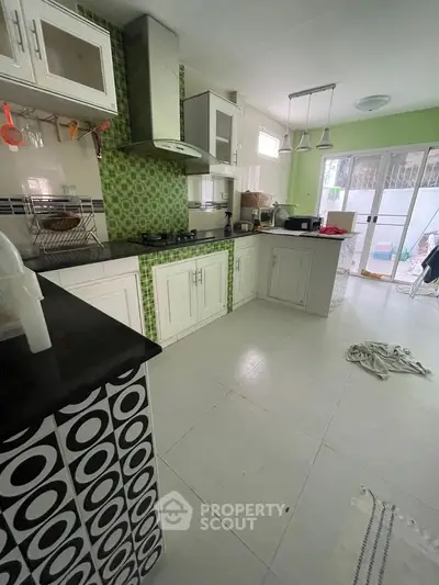 Spacious kitchen with modern design and open layout, featuring stylish green accents and ample natural light.