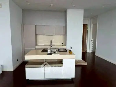 Modern kitchen with sleek design and open layout, featuring a central island and dark wood flooring.