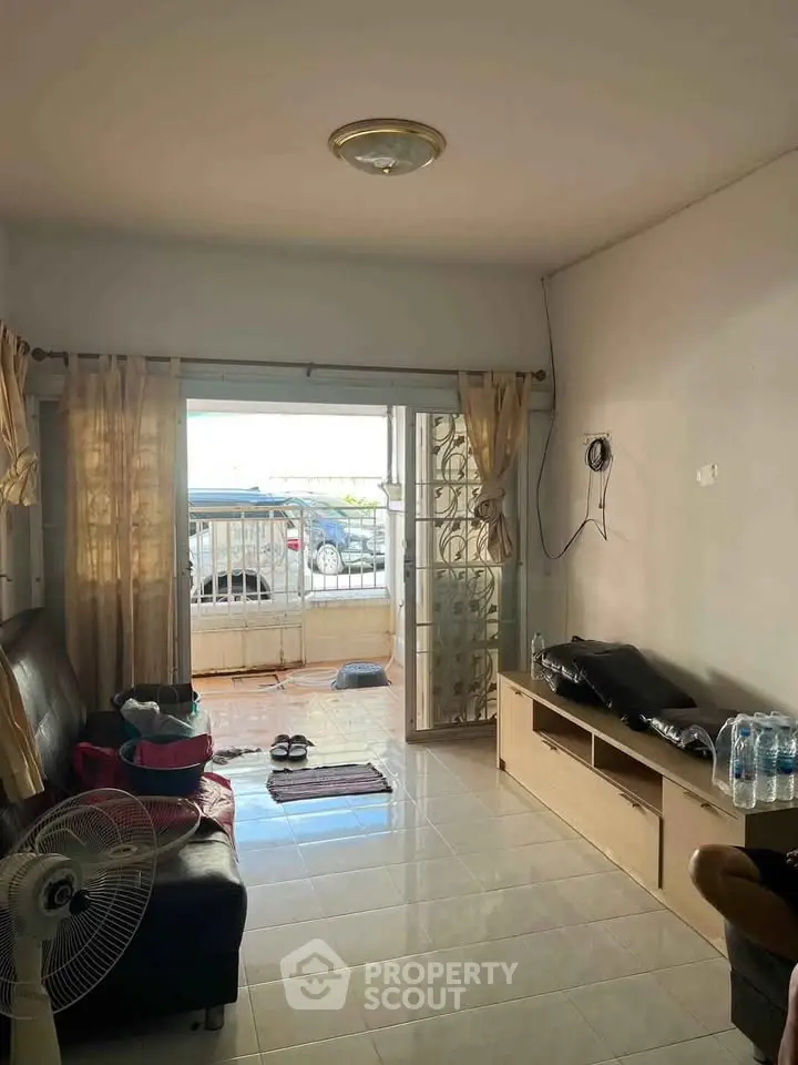 Cozy living room with open view to balcony and parked car outside.