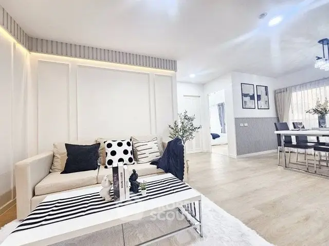 Modern living room with stylish decor and open layout, featuring a cozy sofa and elegant dining area.