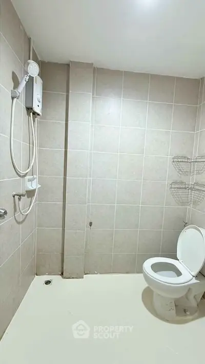 Spacious bathroom with modern shower and toilet in a tiled setting.