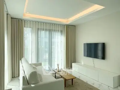 Modern living room with sleek white furniture and large windows offering natural light.