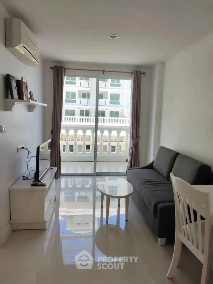 Modern living room with sleek furniture and large window offering natural light and city view.