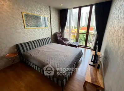 Modern bedroom with large windows and city view, featuring stylish furniture and elegant decor.