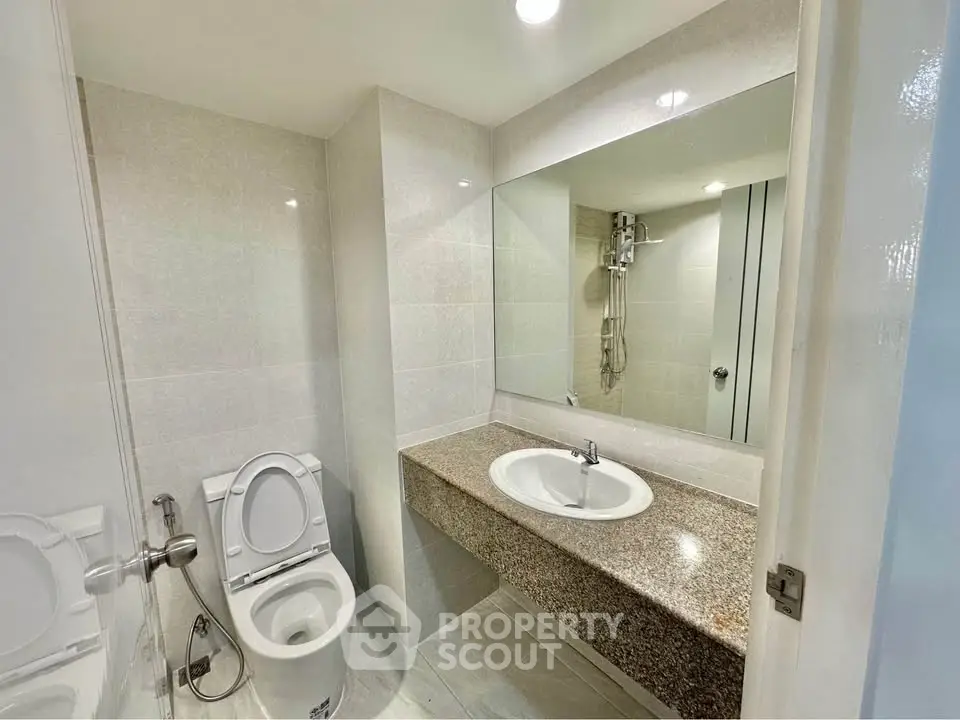 Modern bathroom with sleek design and spacious layout, featuring a large mirror and elegant fixtures.