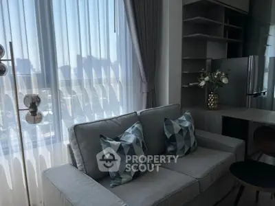 Modern living room with stylish sofa and geometric cushions, featuring a city view through sheer curtains.