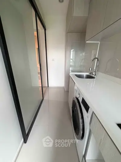 Modern kitchen with sleek cabinetry and built-in washing machine in a compact layout.