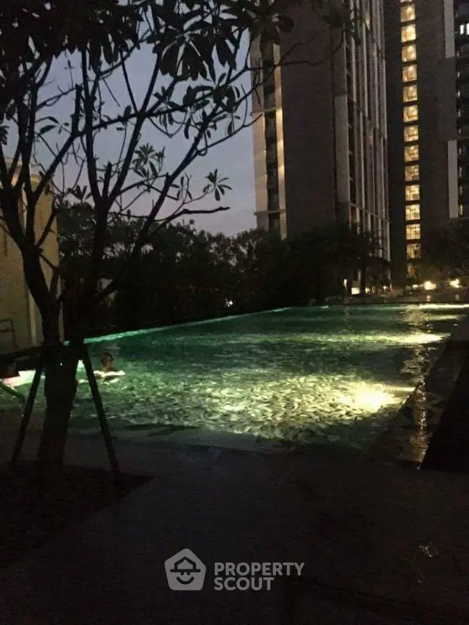 Luxurious illuminated pool area with modern high-rise backdrop at dusk.